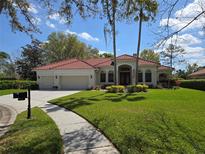 Inviting home with a red tile roof, well-manicured lawn, mature landscaping, and a circular driveway at 9127 Woodridge Run Dr, Tampa, FL 33647