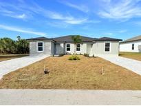 New construction features light gray stucco and paved driveway with low-maintenance landscaping at 12223 Kirk Ave, Port Charlotte, FL 33981