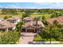 Beautiful home showcasing a tile roof, brick driveway, and lush landscaping with a golf course in the background at 1416 Via Verdi Dr, Palm Harbor, FL 34683
