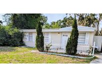 Charming home featuring a welcoming entrance, a well-manicured lawn, and white picket fence at 1906 E 98Th Ave, Tampa, FL 33612