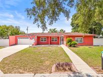Charming one-story home featuring a manicured lawn, attached garage, and vibrant coral exterior paint at 603 Royal Crest Dr, Brandon, FL 33511