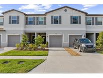 Charming townhouse featuring a two-car garage, landscaped front yard, and neutral color palette at 10472 Shady Preserve Dr, Riverview, FL 33578