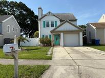 Charming two-story home featuring a well-maintained lawn, white picket fence, and colorful turquoise accents at 10775 Glen Ellen Dr, Tampa, FL 33624