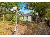 Charming cottage-style home featuring mature trees, lush landscaping and a screened in porch at 1216 E Lambright St, Tampa, FL 33604