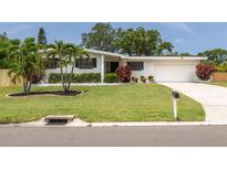 Charming single-story home with lush green lawn, beautiful landscaping, and a white exterior at 1322 Byron Dr, Clearwater, FL 33756