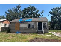 Exterior view of a quaint home needing repairs, featuring a covered roof and front lawn at 2011 Oakwood Ave, Tampa, FL 33605