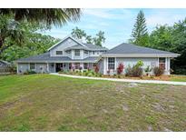 Charming home featuring a manicured lawn, mature trees, and colorful landscaping along a walkway to the front door at 35 Deerpath Dr, Oldsmar, FL 34677
