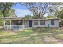 Charming single-story home with a covered porch, painted brick accents, and a spacious front yard at 1506 E Poinsettia Ave, Tampa, FL 33612