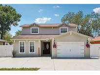 Charming two-story home featuring a well-maintained front yard, attached garage, and decorative floral accents at 6212 N Grady Ave, Tampa, FL 33614