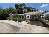 Charming home with a gray exterior, teal doors, covered parking, and white stone landscaping at 6741 4Th Ave N, St Petersburg, FL 33710
