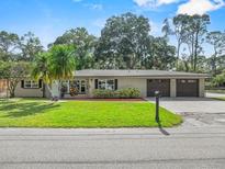 Charming single-story home with a well-manicured lawn, complemented by mature trees and a double car garage at 7137 Wedgewood Dr, New Port Richey, FL 34652