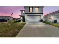 Contemporary two-story home with a long driveway and an attached two-car garage at 7380 Sail Clover Ln, Zephyrhills, FL 33540