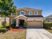 Inviting two-story home featuring a well-manicured lawn, mature trees, and an attached two-car garage at 7852 Stoney Hill Dr, Wesley Chapel, FL 33545