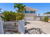 Charming two-story home with blue shutters, a white picket fence, and a spacious driveway at 1210 Bay Pine Blvd, Indian Rocks Beach, FL 33785