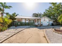 Charming single-story home featuring a metal roof, white exterior with decorative accents, and a well-manicured front yard at 1857 Bayou Grande Ne Blvd, St Petersburg, FL 33703
