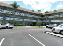 Well-maintained condo building featuring assigned parking, mature palm trees, and decorative facade at 2447 Ecuadorian Way # 11, Clearwater, FL 33763