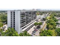 Exterior shot of a high-rise building featuring many balconies, parking, and manicured trees at 3211 W Swann Ave # 605, Tampa, FL 33609
