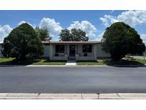 Charming home featuring a covered front porch, complemented by lush landscaping and mature trees at 34300 Countryside Dr, Wesley Chapel, FL 33543