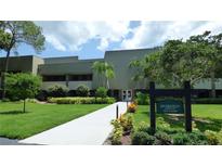 Well maintained condo building with lush lawn, mature landscaping, and decorative sign at 36750 Us 19 N # 15309, Palm Harbor, FL 34684