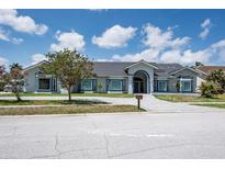 Beautiful single story home featuring a gray tile roof, landscaped yard and stone paver driveway at 4012 Wellington Pkwy, Palm Harbor, FL 34685