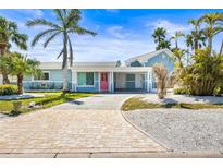 Charming blue exterior with lush tropical landscaping and a welcoming pink front door at 501 Janice Pl, Indian Rocks Beach, FL 33785