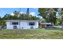 Charming single-story home featuring a fenced yard and covered parking at 6825 Hammock Rd, Port Richey, FL 34668