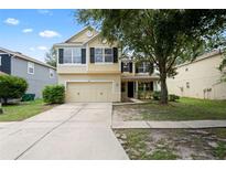 Charming two-story home with attached two-car garage, manicured lawn, and mature trees at 7249 Bridgeview Dr, Wesley Chapel, FL 33545