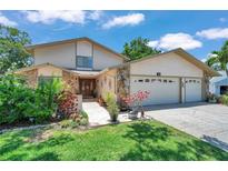 Inviting two-story home with stone accents, manicured lawn, and a three-car garage at 11974 Rosetree S Pl, Seminole, FL 33772
