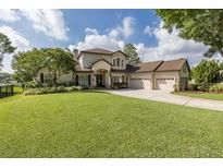 Stately home featuring a lush green lawn, attached three car garage, and manicured landscaping at 1834 Daiquiri Ln, Lutz, FL 33549