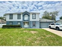 Inviting two-story home featuring a well-manicured lawn and attached two car garage at 3181 Deltona Blvd, Spring Hill, FL 34606