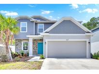 Charming two-story home with gray siding, stone accents, blue door, and a well-maintained front yard at 3602 W Iowa Ave, Tampa, FL 33611