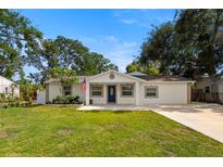 Charming single-story home featuring a well-manicured lawn, mature trees, and a welcoming front entrance with blue door at 4208 W Bay Vista Ave, Tampa, FL 33611