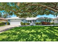 Charming single-story home with a manicured lawn, lush landscaping, and inviting curb appeal under a large tree at 7092 119Th St, Seminole, FL 33772