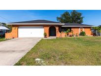 Charming single-story home with a well-maintained lawn, attached garage, and vibrant exterior paint at 3254 Great Neck St, Port Charlotte, FL 33952