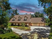 Stunning home with three dormers, mature trees, and a circular drive surrounded by landscaped garden beds at 1141 Myrtle Rd, Valrico, FL 33596