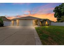 Charming single-story home with a well-manicured lawn and attached two-car garage at sunset at 12804 Bert Pl, Tampa, FL 33625
