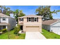 Charming two-story home with a well-maintained lawn and a two-car garage at 13727 Whiskey Daisy Dr, Dade City, FL 33525