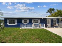 Charming blue single-story home featuring a well-manicured lawn and a cozy front patio with white picket fence at 13920 Berkowitz Ave, Hudson, FL 34667