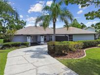 Charming single-story home featuring mature landscaping, a circular driveway, and a welcoming entrance at 14170 Fennsbury Dr, Tampa, FL 33624