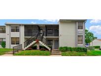 Condo exterior featuring well-kept lawn, black railings, concrete stairs leading to units, and neutral paint scheme at 1905 Oyster Catcher Ln # 924, Clearwater, FL 33762