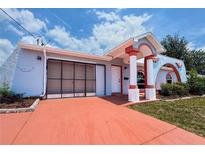 Charming single-story home showcasing its unique architectural style with an arched entryway and colorful accents at 2432 Caretta Ave, Spring Hill, FL 34609