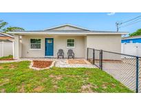 Charming single-story home with blue door, gray chairs, tidy landscaping, and a welcoming walkway at 3927 Spence Ave, Tampa, FL 33614
