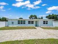 Charming single-story home featuring a brick-paved driveway, white exterior and EV charger at 4005 W Coachman Ave, Tampa, FL 33611