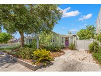 Charming home featuring a light green exterior, well-maintained landscaping, and a welcoming purple front door at 427 21St N Ave, St Petersburg, FL 33704