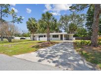 Charming single-story home featuring a well-manicured lawn and a concrete driveway at 695 Sunset Dr, Tarpon Springs, FL 34689