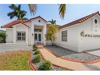 Charming home featuring lush landscaping, a red tile roof, and a welcoming entrance at 77 Gulfwinds Dr, Palm Harbor, FL 34683