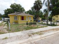 Charming yellow single-story home featuring a red front door, secure chain-link fence, and mature palm trees in the front yard at 844 20Th S St, St Petersburg, FL 33712