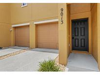 Welcoming front entrance and garages of this charming home with a black door and space for two cars at 9013 White Sage Loop, Lakewood Ranch, FL 34202