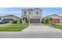 Charming two-story home featuring a two-car garage, a brick-paved driveway and lush landscaping at 11847 Brighton Knoll Loop, Riverview, FL 33579