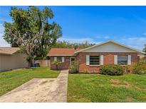Charming brick home featuring a well-manicured lawn, concrete driveway, and mature trees at 13046 Leverington St, Tampa, FL 33624